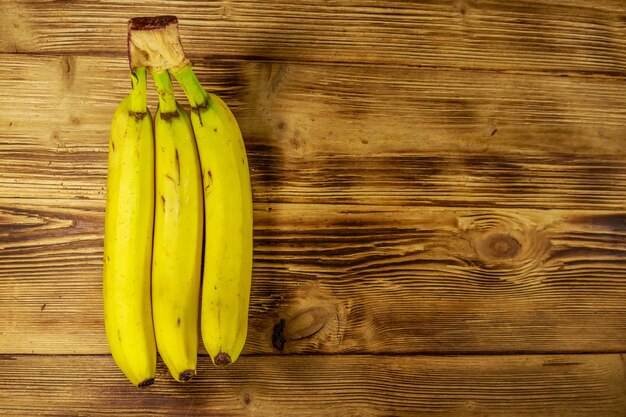 Delicious ripe yellow bananas on wooden table Top view copy space