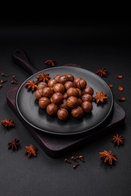 Delicious roasted macadamia nuts in shell on a dark textured background