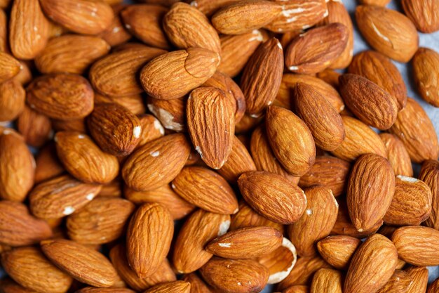 Delicious roasted sweet almonds lie in a large heap, nuts close-up