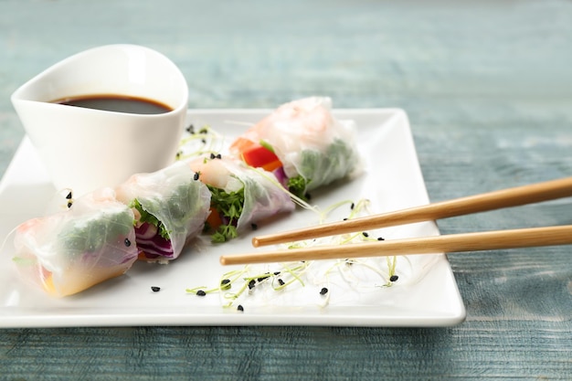 Delicious rolls wrapped in rice paper served on light blue wooden table