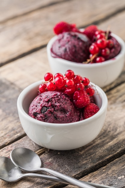 Delicious and romantic dessert. A ball of homemade raspberry walrus with fresh berries  in a white cup on a wooden  background. Close up