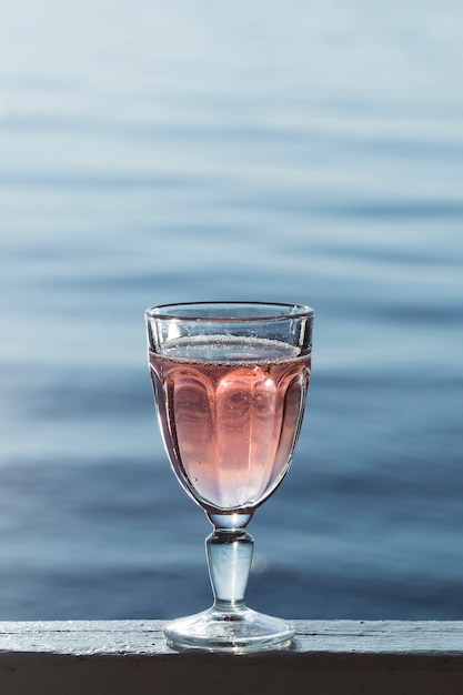 Foto delizioso vino rosato in un bicchiere vicino al mare