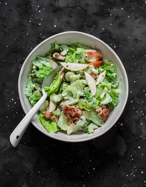 Delicious salad with baked turkey apple celery green salad and Greek yogurt on a dark background top view