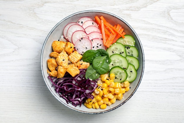 Delicious salad with chicken vegetables and spinach on white wooden table top view