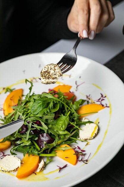 Delicious salad with figs arugula and goat cheese on white plate top view