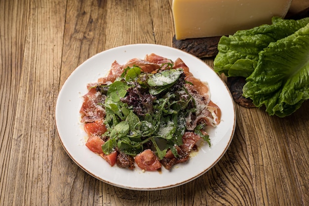 delicious salad with parmesan jamon tomatoes on a white plate