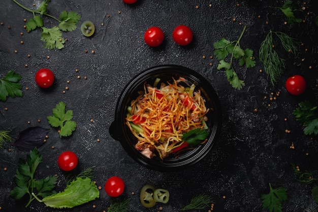 Delicious salad with tomatoes, roasted potatoes, tomatoes and fresh herbs, a fresh salad on the menu of a fast food restaurant on a dark stone table. Healthy option of fast food.