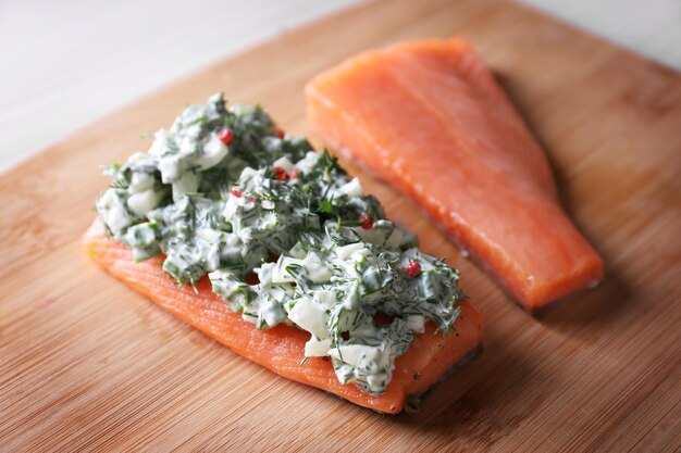 Foto filetto di salmone delizioso con erbe in salsa di panna su tagliere di legno