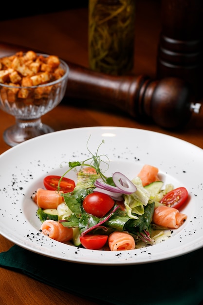 delicious salmon salad in a white plate on a wooden table