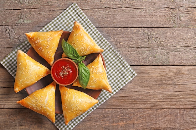 Photo delicious samsa with sauce and basil on a wooden table. top view