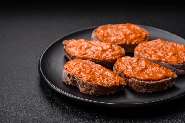 Delicious sandwich consisting of toast red sauce with salt spices and herbs on a dark concrete background