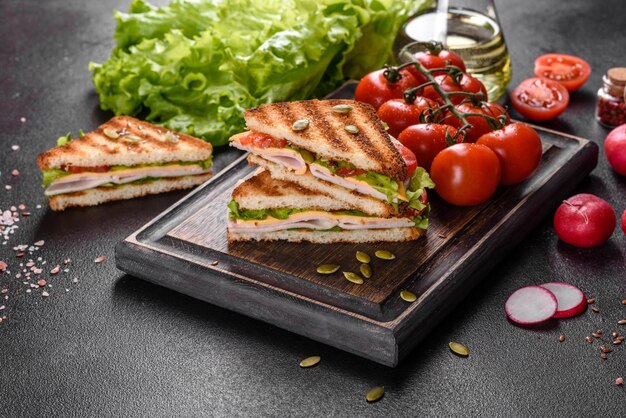 Foto delizioso panino con toast di prosciutto croccante, lattuga e pomodori.