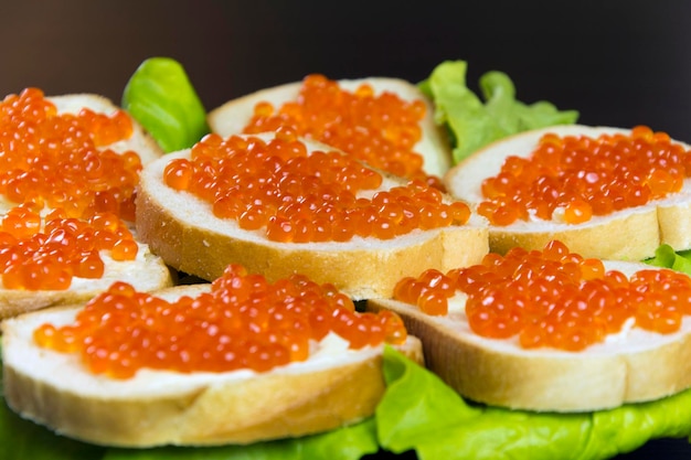 Delicious sandwich with red caviar butter and fresh lettuce leaves on a plate