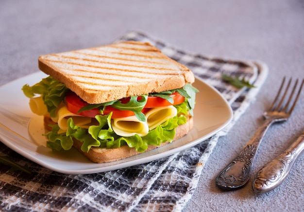 Вкусный бутерброд с поджаренным хлебом, салатом, сыром и помидорами Здоровая домашняя закуска