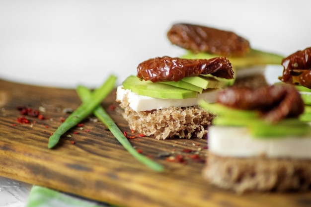 Deliziosi panini con formaggio avocado e pomodori secchi concetto di primo piano per alimenti sani e vegetariani