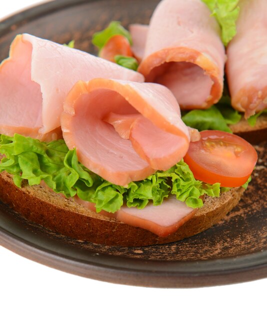 Delicious sandwiches with lettuce and ham on plate closeup