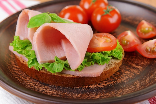 Delicious sandwiches with lettuce and ham on plate on table closeup