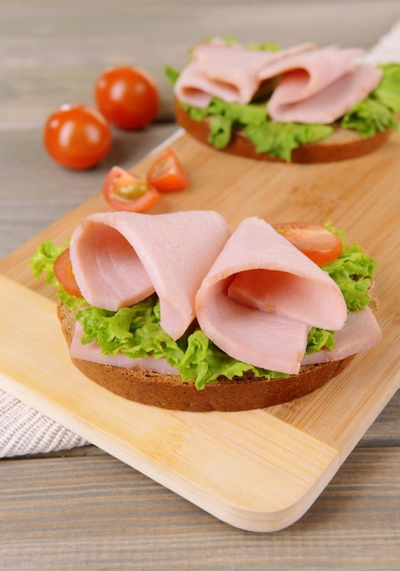 Photo delicious sandwiches with lettuce and ham on table closeup