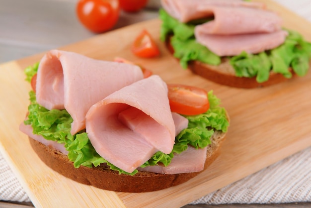 Delicious sandwiches with lettuce and ham on table closeup