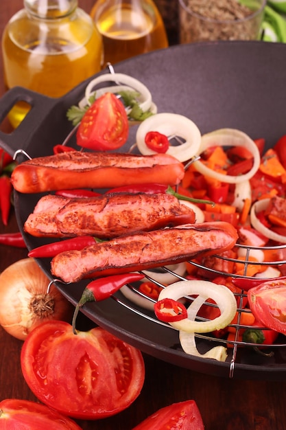 Delicious sausages with vegetables in wok closeup