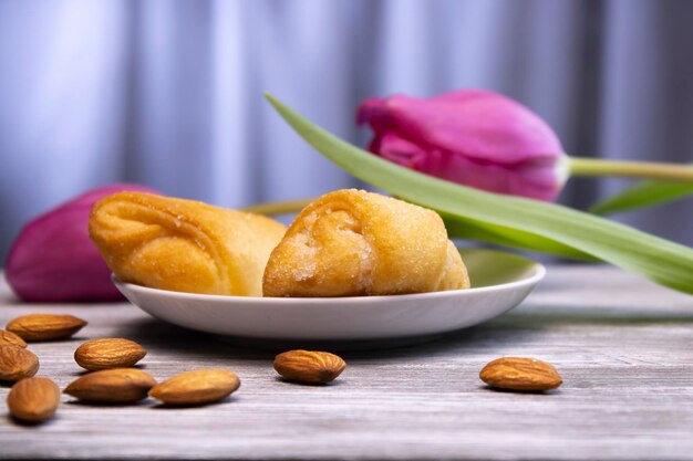 Photo delicious shortbread cake with lilac tulips in the background and almonds