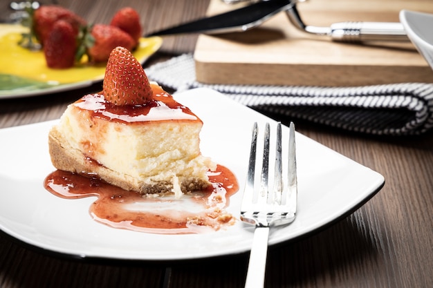 Foto deliziosa fetta di cheesecake alle fragole su un piatto bianco su un tavolo di legno