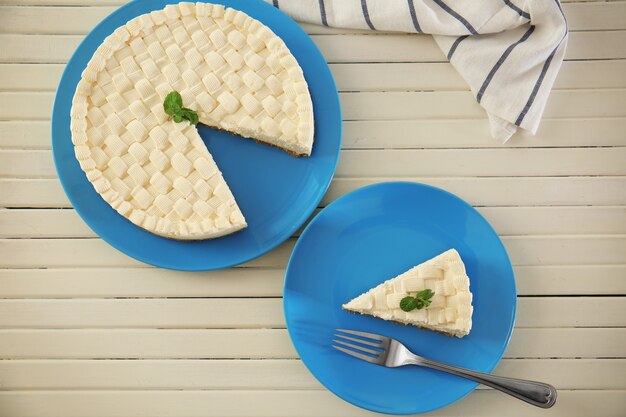 Delicious sliced cheesecake on wooden table