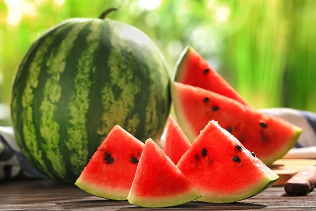 Delicious sliced watermelon on wooden table against blurred