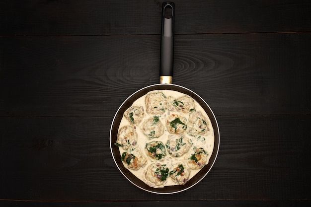 Delicious small meatballs with spinach in a creamy sauce in the frying pan