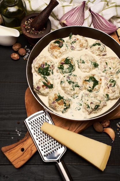 Delicious small meatballs with spinach in a creamy sauce in the frying pan