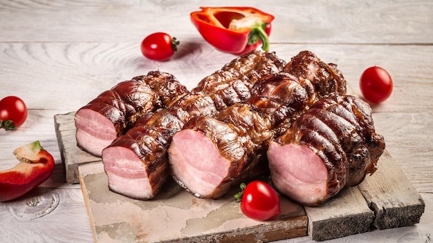 Delicious smoked ham on a wooden board with vegetables Natural product from organic farm produced by traditional methods