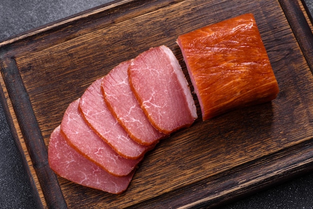 Deliziosa carne affumicata tagliata a fette su un tagliere di legno