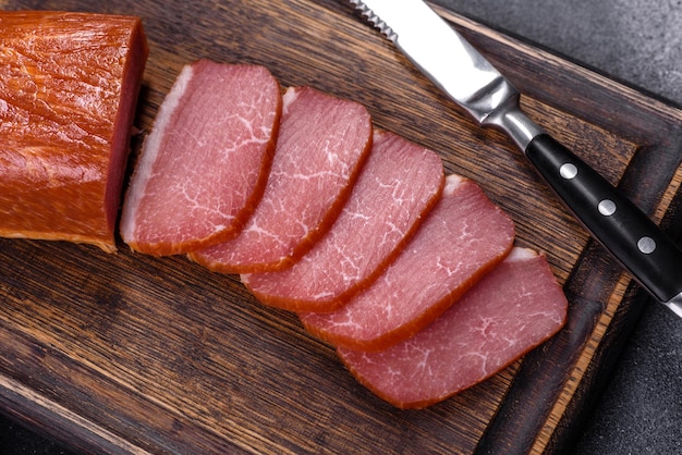 Delicious smoked meat cut with slices on a wooden cutting board