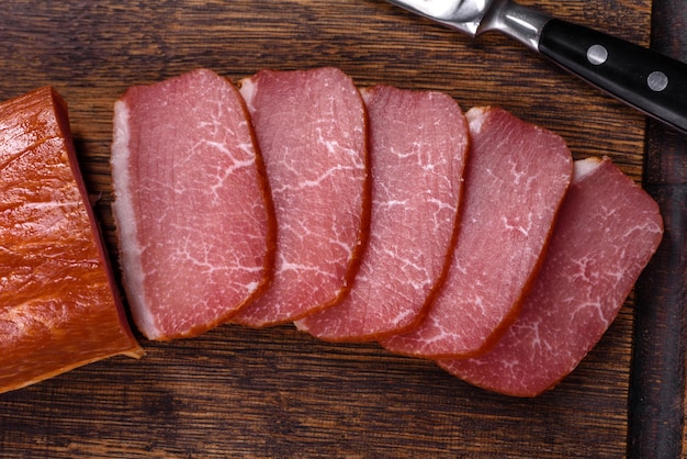 Delicious smoked meat cut with slices on a wooden cutting board