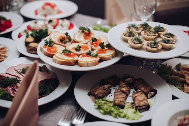 Delicious snacks on plates at banquet. Variety of cold snacks served on plates at banquet