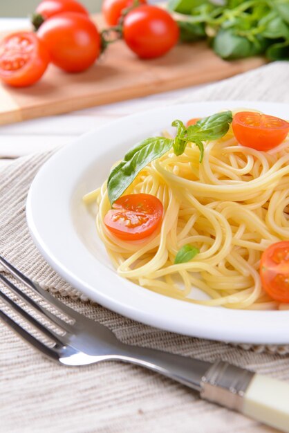 Delicious spaghetti with tomatoes on plate on table closeup