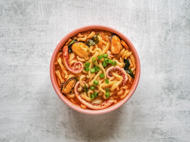 Delicious spicy seafood noodle soup in the light background. Top view, copy space.