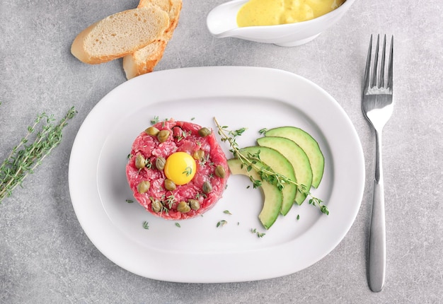 Delicious steak tartare with yolk and capers on plate