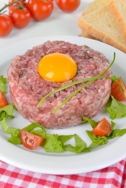 Delicious steak tartare with yolk on plate on table closeup