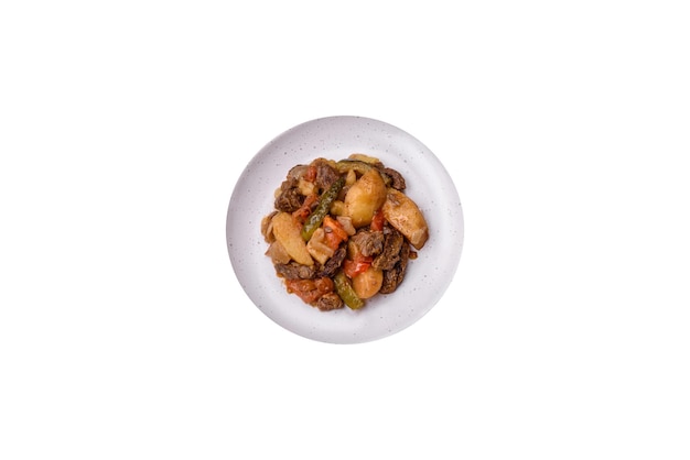 Delicious stew with potatoes tomatoes beef onions and carrots on a ceramic plate on a dark concrete background