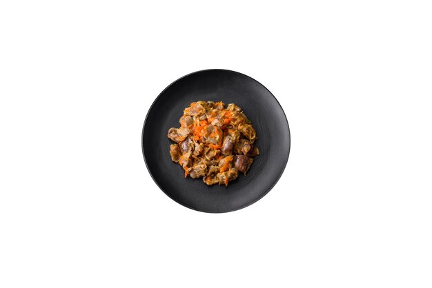 Delicious stewed chicken gizzards with carrots and tomato on a dark concrete background