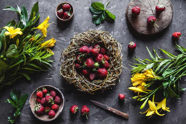 빈티지 화 환에 어두운 회색 표면에 노란색 꽃과 함께 맛있는 딸기. 건강 식품, 과일