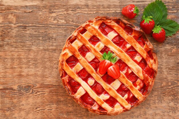 Delicious strawberry cake on wooden background