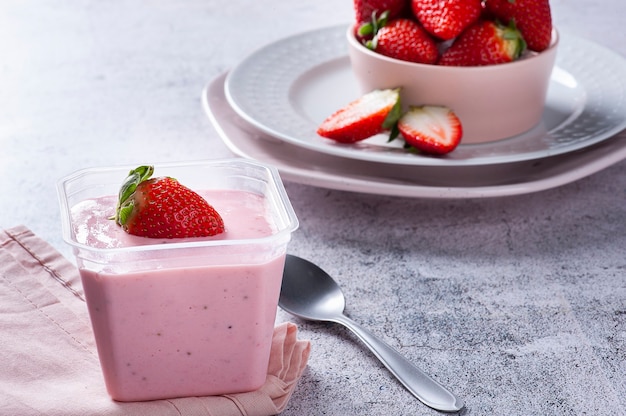 Deliziosa mousse alla fragola in un bicchiere di plastica per la consegna con fragole fresche. copia spazio