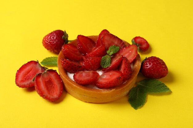 Delicious strawberry tart on yellow background, close up.