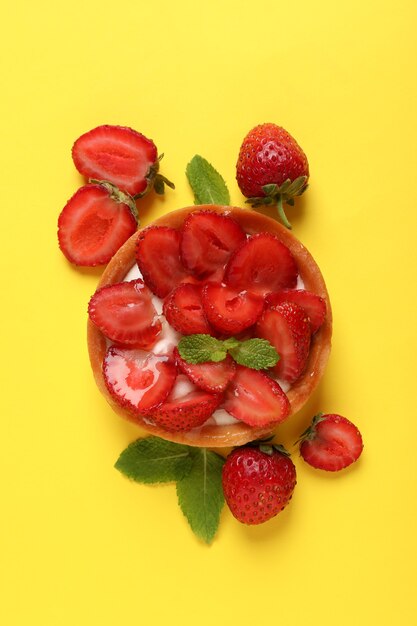 Delicious strawberry tart on yellow background, top view.