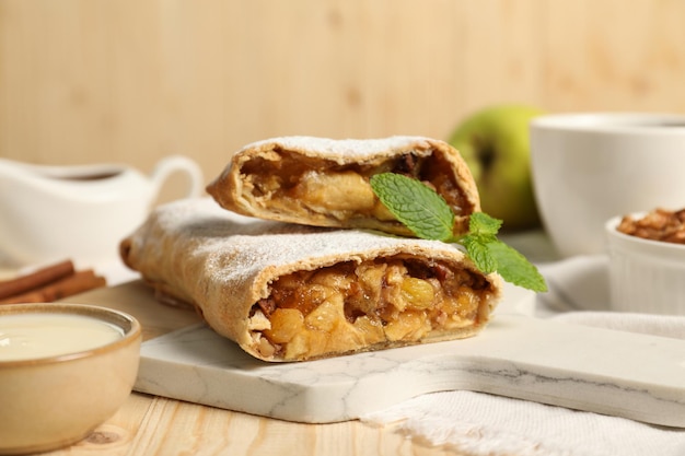 Photo delicious strudel with apples nuts and raisins on wooden table closeup