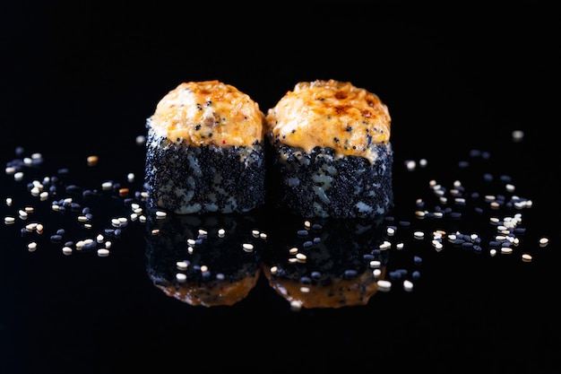 Delicious sushi roll with fish and sesame on a black background with reflection Menu and restaurant  