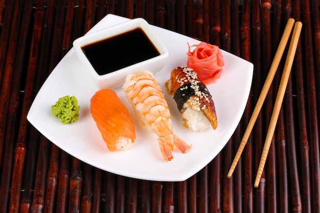 Delicious sushi served on plate on bamboo mat