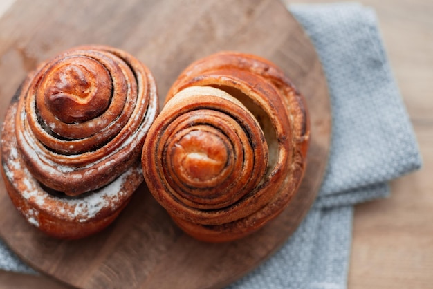 Delicious sweet buns lie on a wooden round board on the kitchen top view Baking